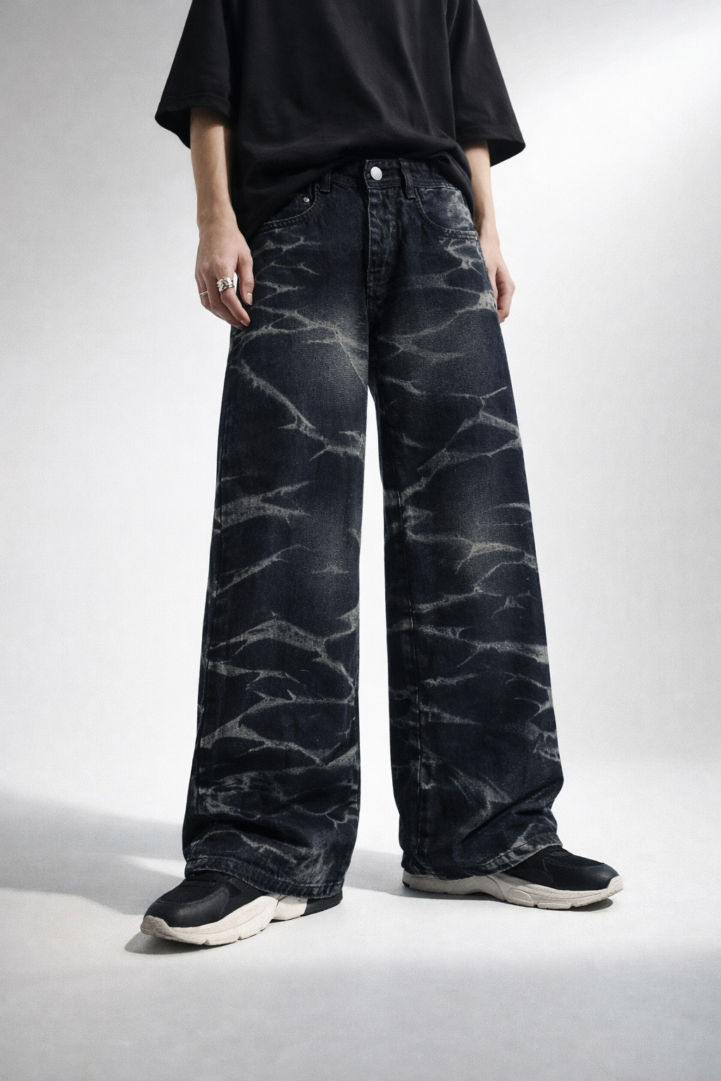 Person wearing black acid-wash jeans on a white background